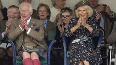 an older man and woman sitting next to each other at a sporting event with their hands in the air