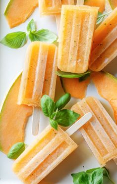 several popsicles are arranged on a plate with basil leaves and watermelon slices