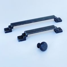 two black handles and knobs on a white surface