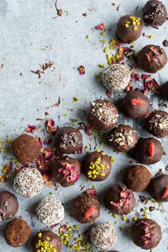 chocolate truffles with sprinkles scattered around them on a gray surface