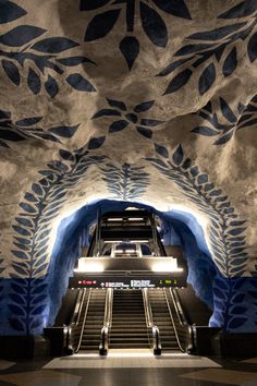 an escalator in a building with blue and white designs on the walls, along with stairs