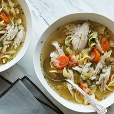 two bowls of chicken noodle soup on a marble table