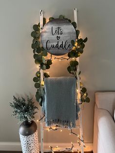 a ladder decorated with greenery, lights and a sign that says let's cuddle