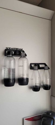 there are four jars hanging on the wall next to a toaster and coffee pot