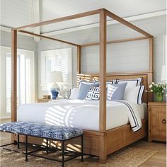 a bedroom with a four poster bed and blue accents on the pillows, along with a bench