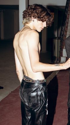 a shirtless man in black leather pants