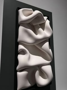 a black and white sculpture with wavy shapes on it's side, in front of a gray wall