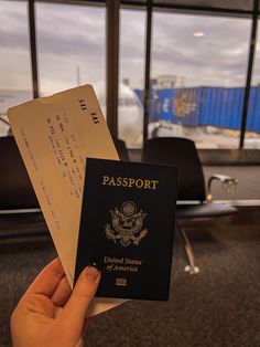 a person holding up a passport in front of an airport terminal with the door open