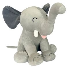 an elephant stuffed animal sitting on top of a white surface with its trunk up in the air