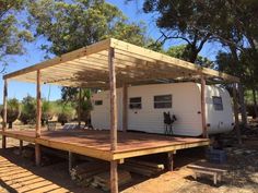 a mobile home sits in the middle of a dirt lot with trees and bushes around it