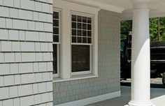 a black and white fire hydrant sitting in front of a gray brick building with two windows