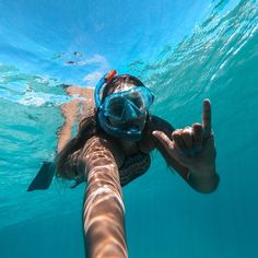 a woman is swimming in the water with her hand up