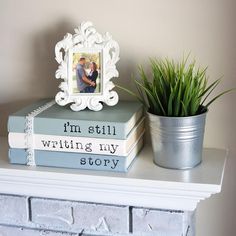 a stack of books sitting on top of a white mantle next to a potted plant