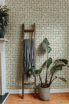 a plant in a pot next to a chair and wallpaper with leaves on it