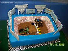 a cake made to look like a dirt track with cars and trucks in the middle