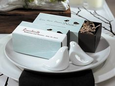 two white birds sitting on top of a plate next to a box of chocolates