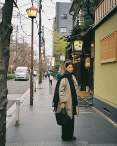 a woman is walking down the street with her hand on her hip and looking at the camera