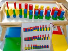 an assortment of colorful plastic objects on display in front of a wooden tray filled with paper