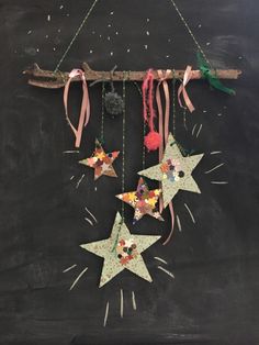 three stars hanging from a string on a blackboard