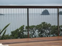 a wooden deck overlooking the ocean with trees in the foreground and an island in the distance