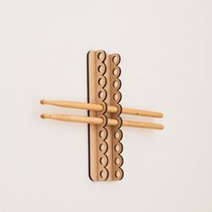 three wooden toothbrush holders with holes in them on a white surface, one is holding two wood sticks