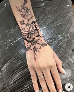 a woman's hand with a flower tattoo on her left arm and the wrist