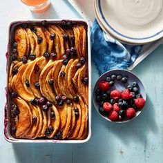 a pan filled with blueberries and bananas next to bowls of fruit on a table