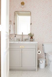 a bathroom with pink and white wallpaper, a mirror, sink and toilet in it