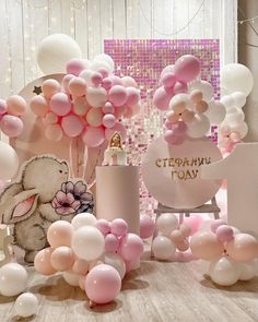 pink and white balloons are on the floor next to a table with an elephant bottle