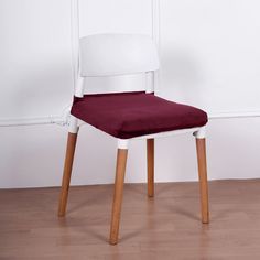 a white chair with a purple cushion on top of it in front of a wall