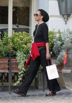 a woman walking down the street with headphones in her ears and carrying shopping bags