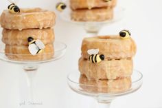 three donuts with bees on them sitting in glass cups