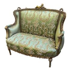 an ornately decorated green couch with gold trimmings on the arms and back