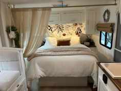 a white bed sitting next to a window in a bedroom under a canopy with curtains