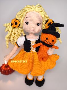 a crocheted doll with blonde hair holding a stuffed pumpkin and wearing an orange dress