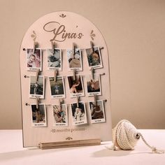 a white photo frame with photos attached to it and a rope on the table next to it