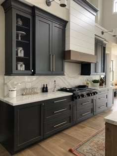 a kitchen with gray cabinets and white counter tops, an oven and stove top in the center