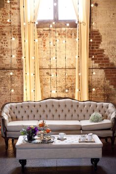 a living room with a couch, coffee table and lights on the wall behind it