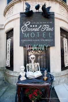 a skeleton statue sitting on top of a table in front of a building with a sign