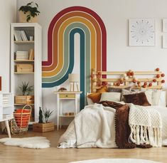 a bed room with a neatly made bed and a rainbow wall mural