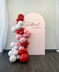 a balloon arch with red, white and pink balloons