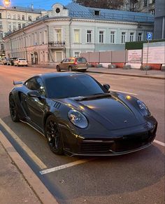 a black sports car is parked on the side of the road in front of some buildings