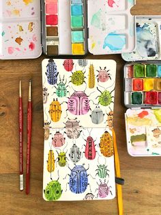 an artist's kit with watercolors, paints and brushes on a wooden table