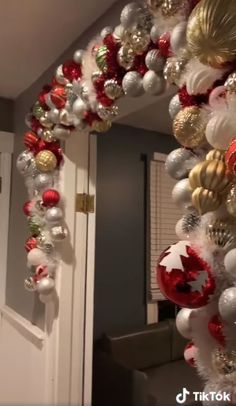 a christmas wreath with ornaments hanging from it's side in front of a door