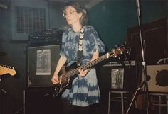 a woman standing in front of a bass guitar