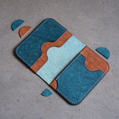 a blue and brown wallet sitting on top of a gray floor with holes in it