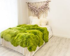 a bedroom with white walls and green fur on the bed