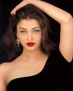 a woman in a black dress with red lipstick and large earrings on her head, posing for the camera