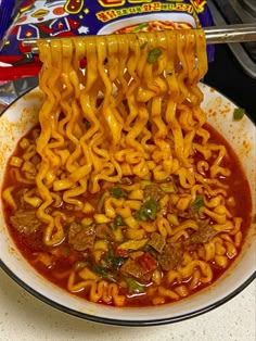 noodles being lifted from a bowl with chopsticks