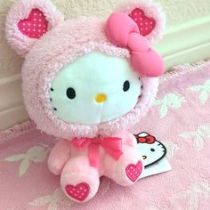 a hello kitty stuffed animal sitting on top of a pink blanket